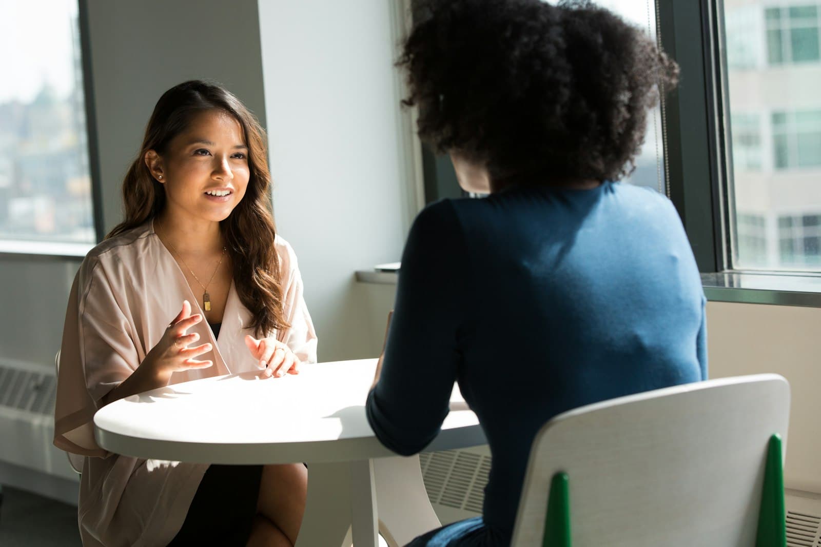 Two women in a warm, sunlit one-on-one conversation — the welcoming feel of a session at Fort Lee Therapy